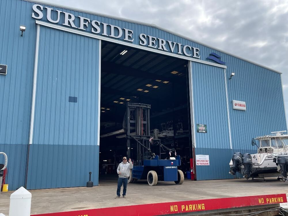Surfside Marina boat service center A man stands outside a large blue building with "Surfside Service," a boat service center with boats and equipment visible inside