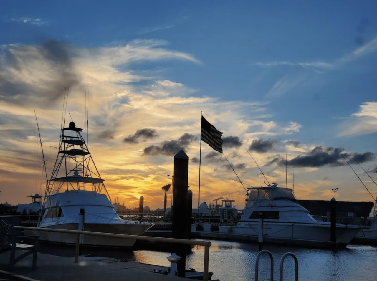 Surfside Marina sunset Two boats docked in transient slips at Surfside Marina during sunset, with a flagpole and American flag between them