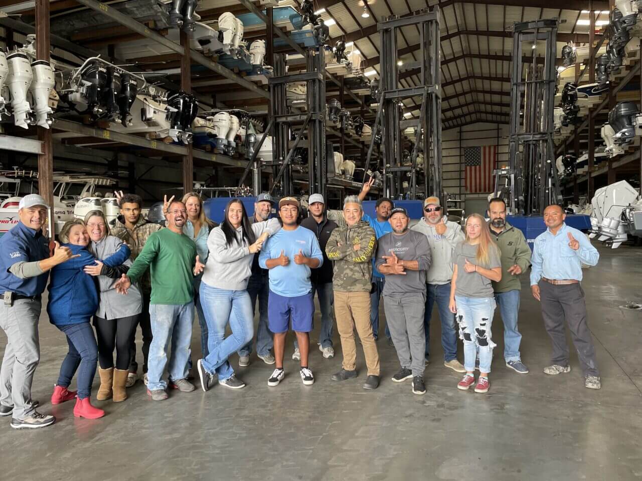 The Surfside Marina staff pose smiling indoors in a large boat storage and service center, surrounded by machinery and equipment.
